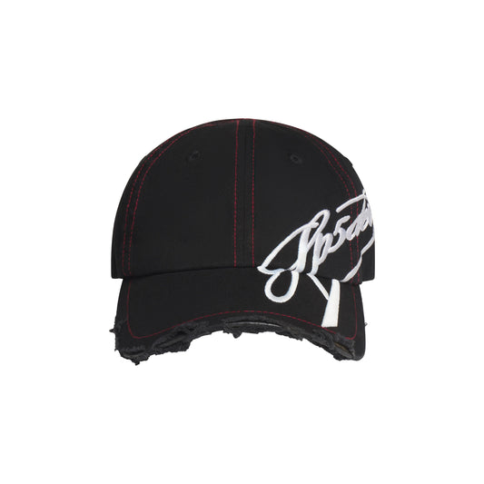 Black baseball hat with red stitching, distressed brim, and white cursive graphic embroidery extending to the side.