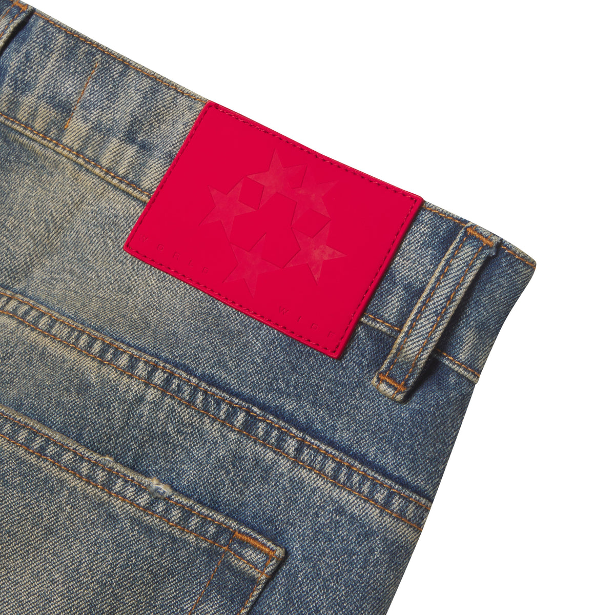 Faded blue denim jeans featuring a bright red leather back patch with a star graphic print and branded detailing.