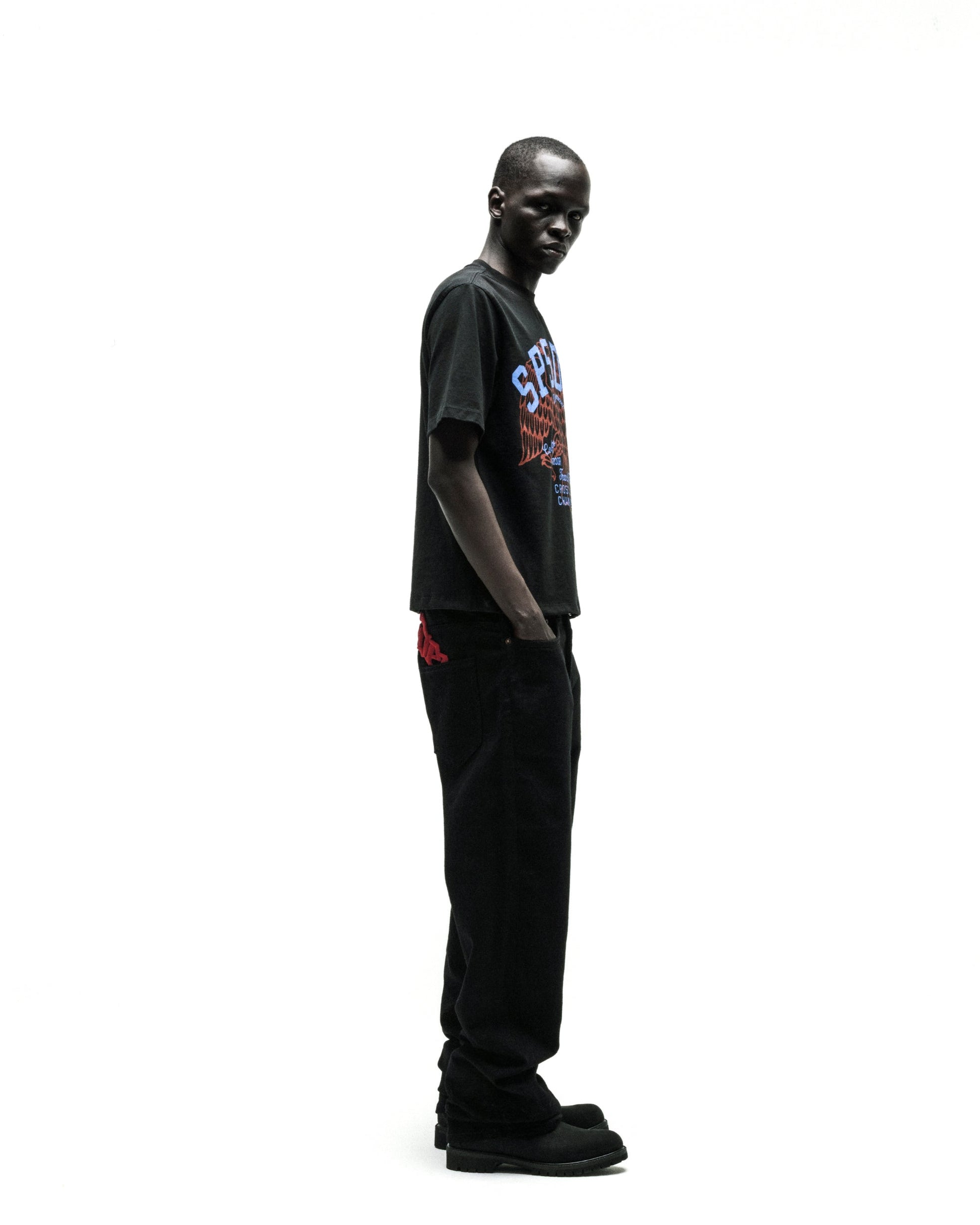 Black Champions League tee with a colorful graphic, paired with black jeans and shoes.