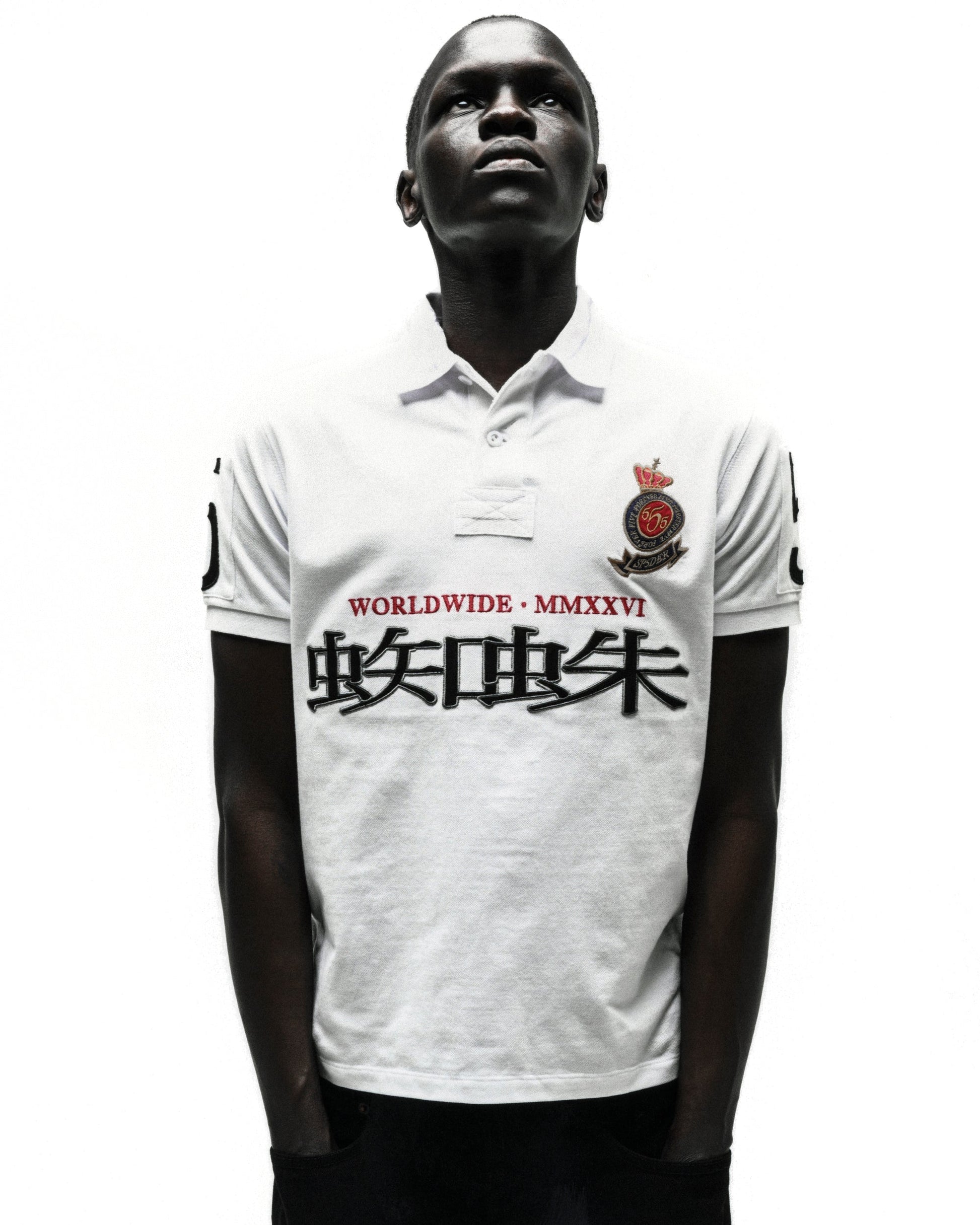 White WORLDWIDE POLO shirt with black Japanese characters, "WORLDWIDE · MMXXVI" text, and crest logo.