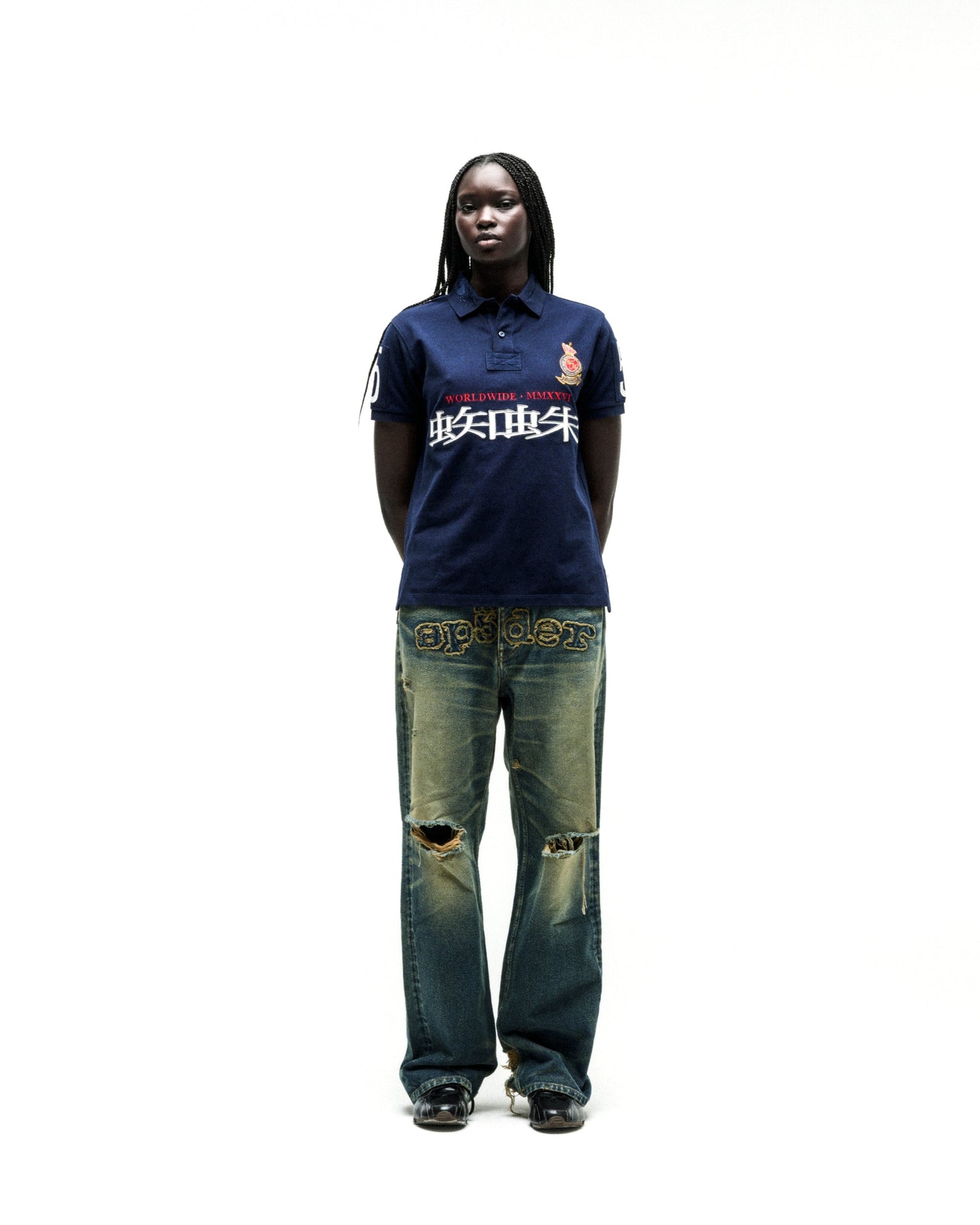 Navy WORLDWIDE POLO with red and white graphic text, worn by a model with distressed denim jeans.