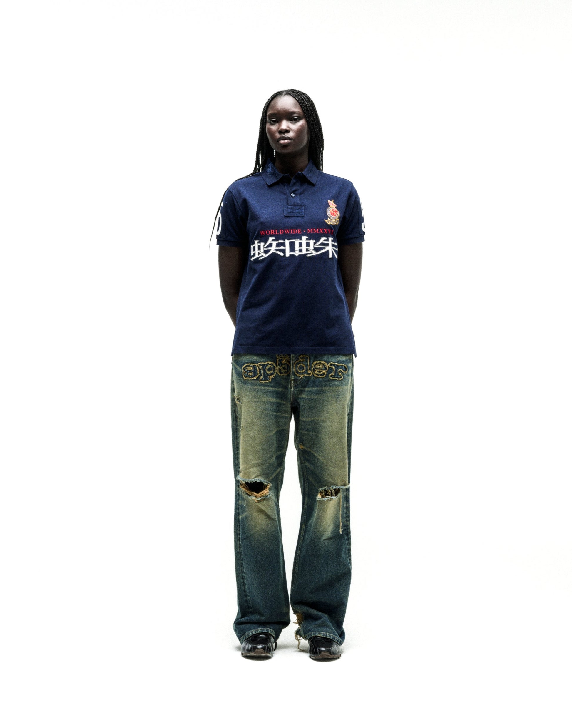 Navy WORLDWIDE POLO with red and white graphic text, worn by a model with distressed denim jeans.