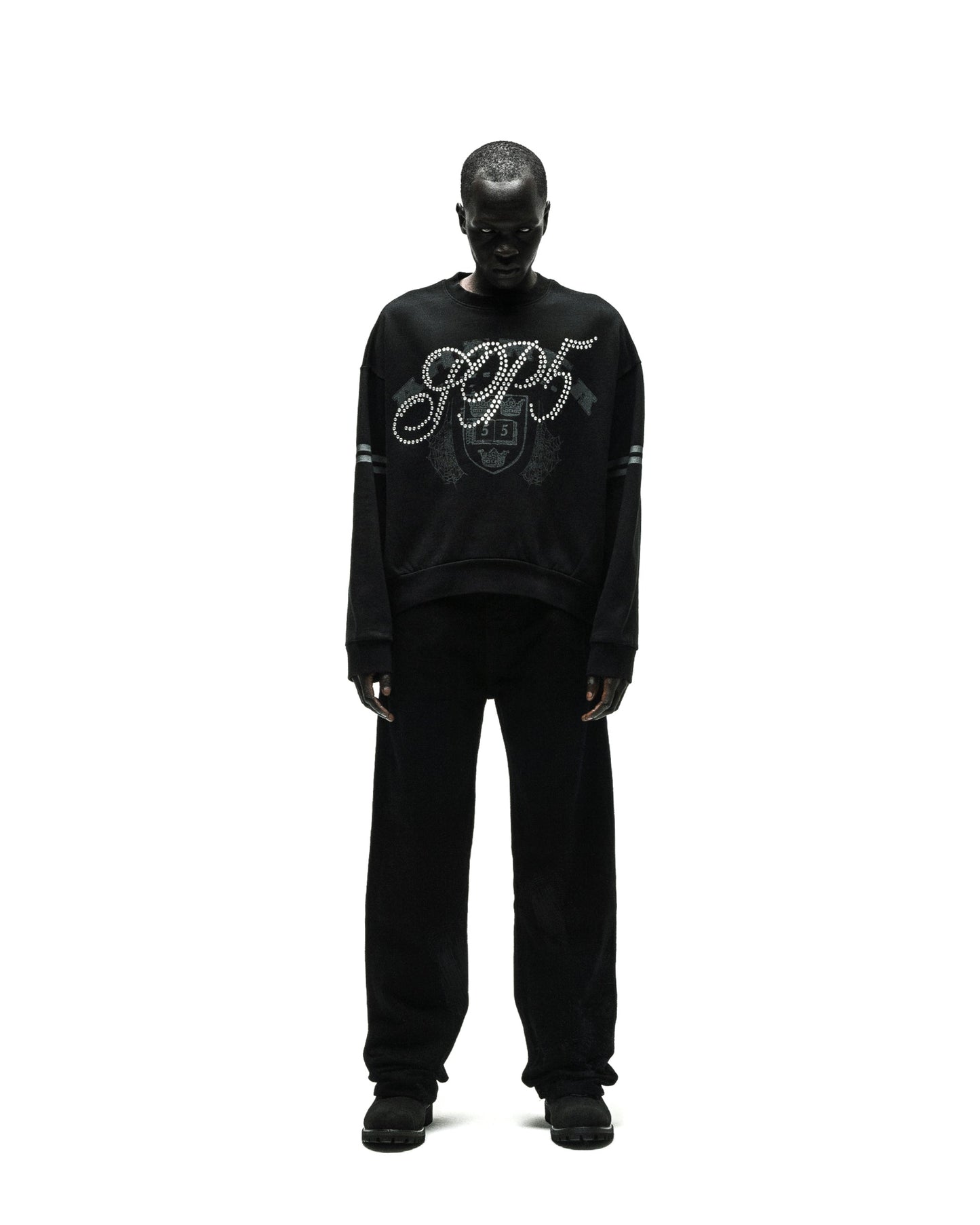 Black ARANEA CREWNECK with "SP5" rhinestone logo and striped sleeves, worn by a model.